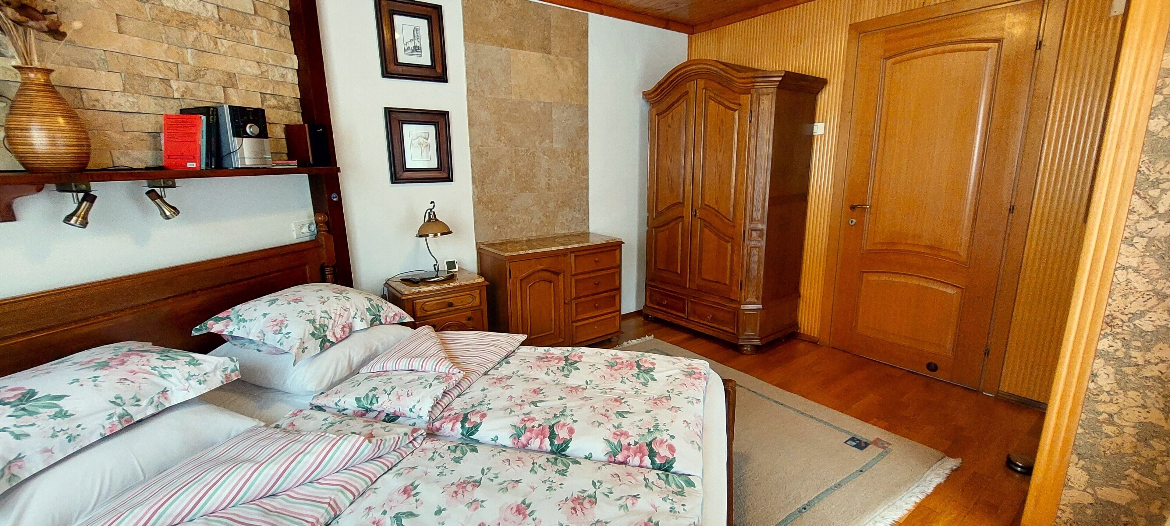 A bedroom with a wooden bed, a nightstand, a dresser, and a wardrobe.