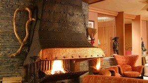 Un salón acogedor con una gran chimenea de piedra, un sillón cómodo y un sofá.