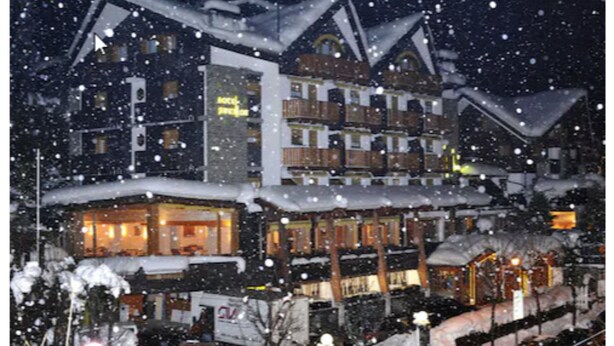 Un hotel de varios pisos con balcones y techos cubiertos de nieve.