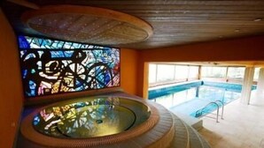 Zona de hidromasaje con un vitral, una piscina y vistas al exterior.