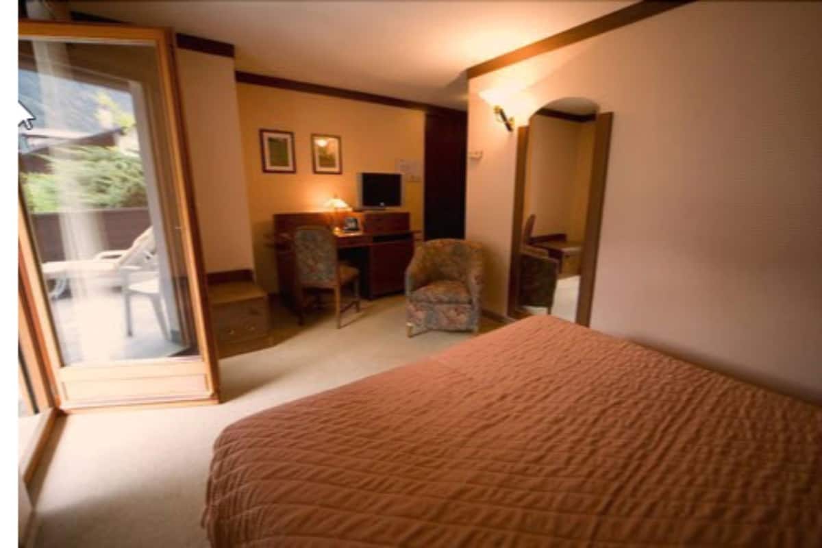 Un dormitorio con cama, escritorio, silla y un espejo grande.