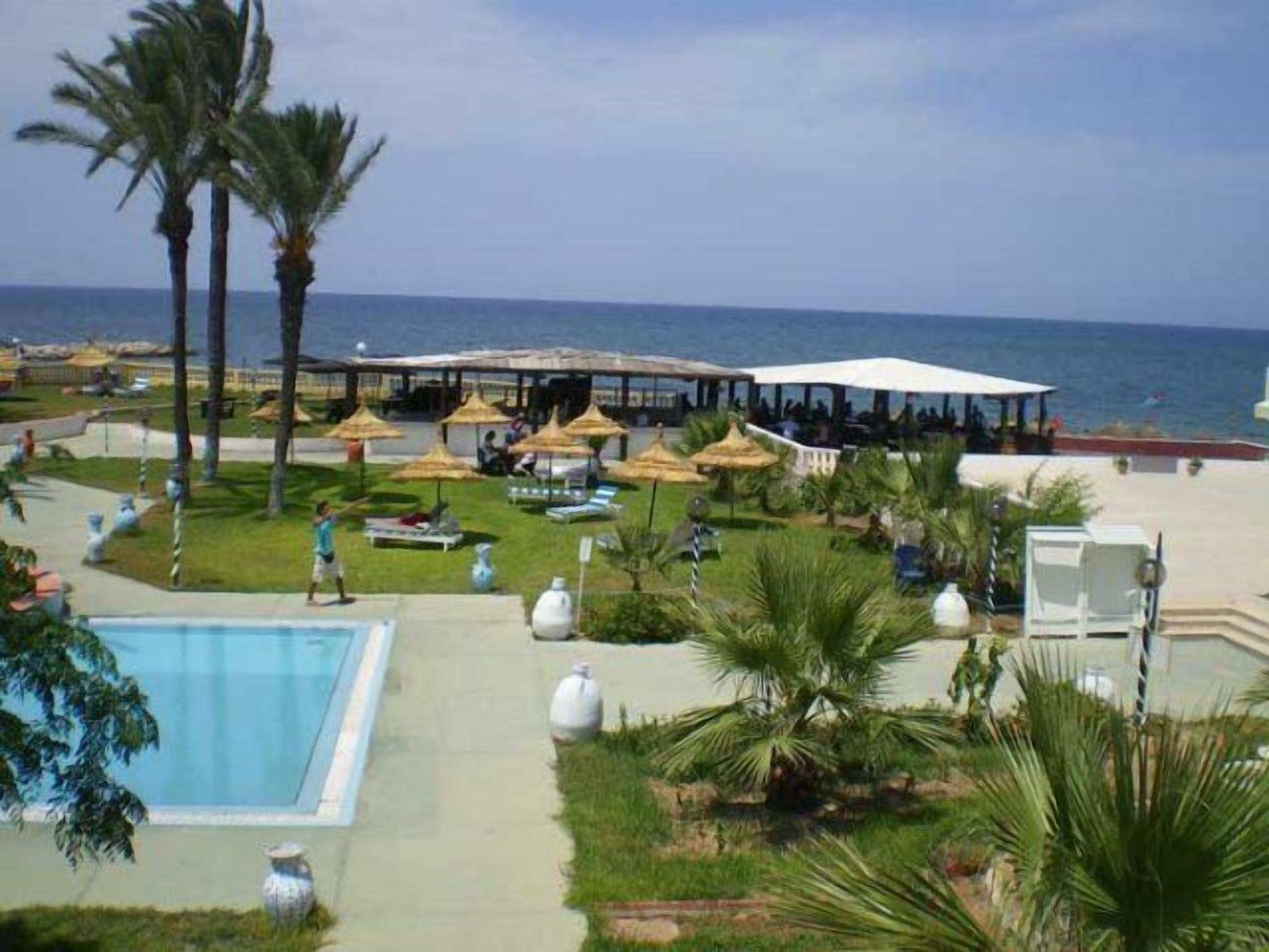 Ein Resort mit Pool, Palmen und Blick auf den Strand.