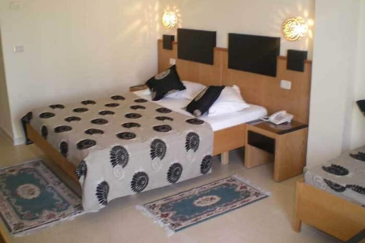 Habitación de hotel con cama, dos mesitas de noche y un pequeño rincón de descanso.