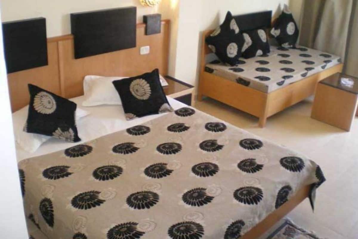 Una habitación de hotel con una cama, una mesita de noche y otra mesita auxiliar.
