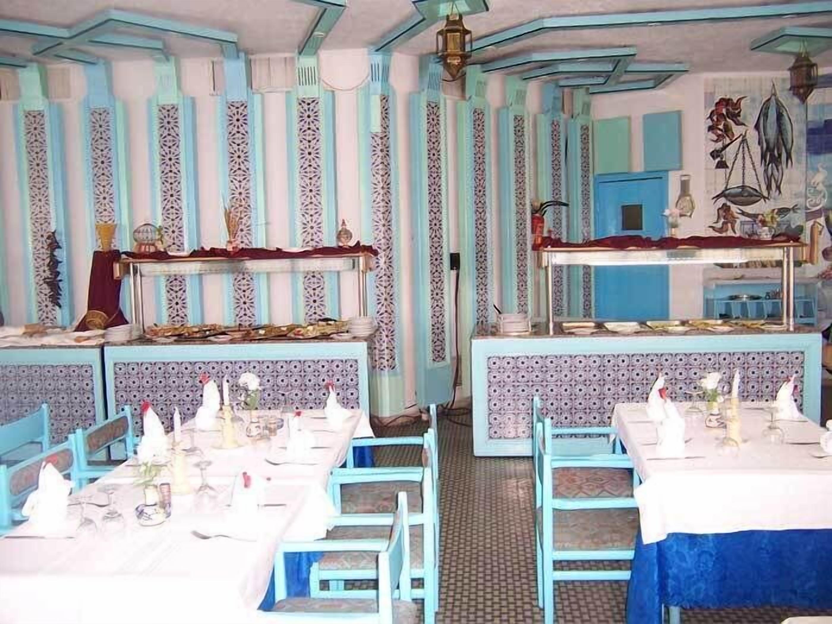 A dining area with blue and white striped walls, patterned wallpaper, and blue chairs and tables.