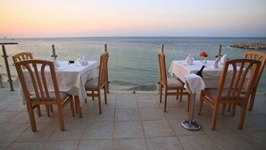 Un restaurante frente al mar con mesas y sillas dispuestas para comer, con vista al océano.