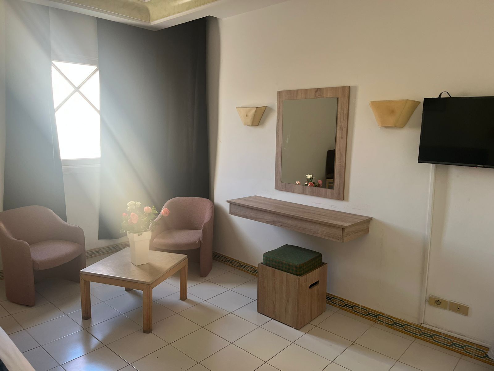 Una sala de estar moderna con dos sillones, una mesita, un espejo, un televisor y un estante de madera.