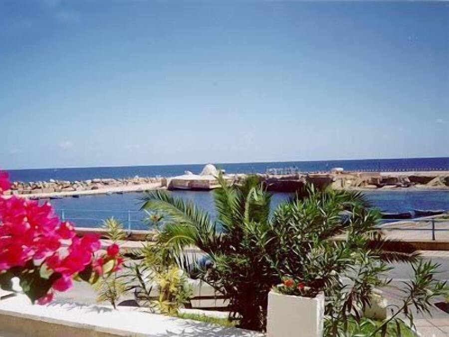 Vista costera con cielo despejado, un puerto deportivo y un puente.