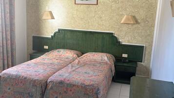 Un letto matrimoniale con biancheria da letto floreale, due comodini con lampade, un quadro appeso alla parete e una testiera verde.