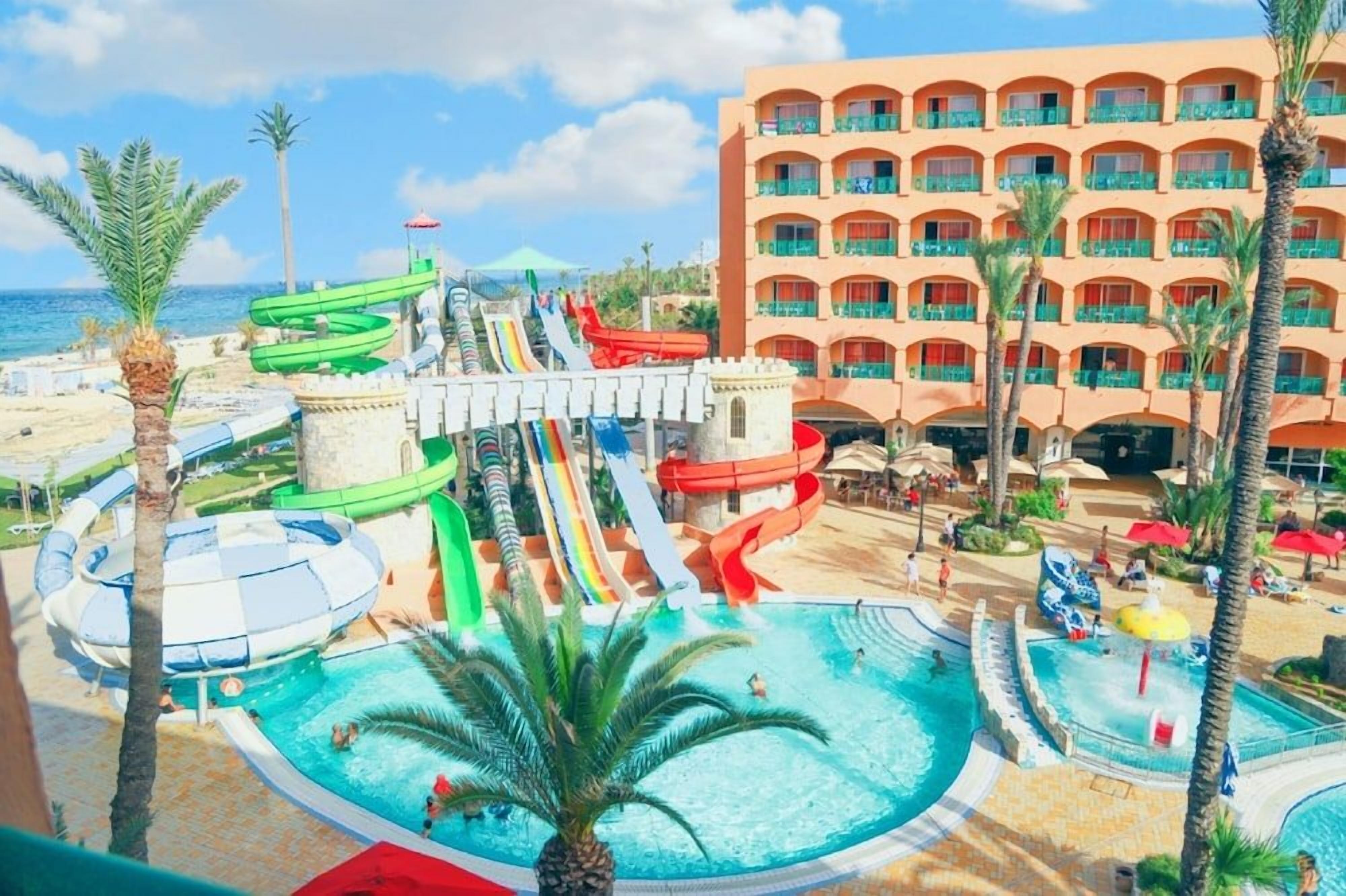 Un resort con parque acuático, piscina y un edificio con balcones.