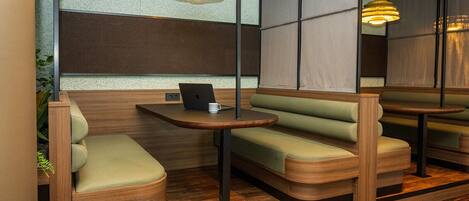 A modern seating area with cushioned booths, a wooden table, and pendant lighting.