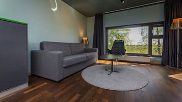 A modern living room with a grey sofa, a round table, and a black chair.