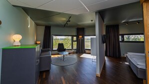 Une pièce moderne comprenant un canapé, un fauteuil, une petite table et un téléviseur.