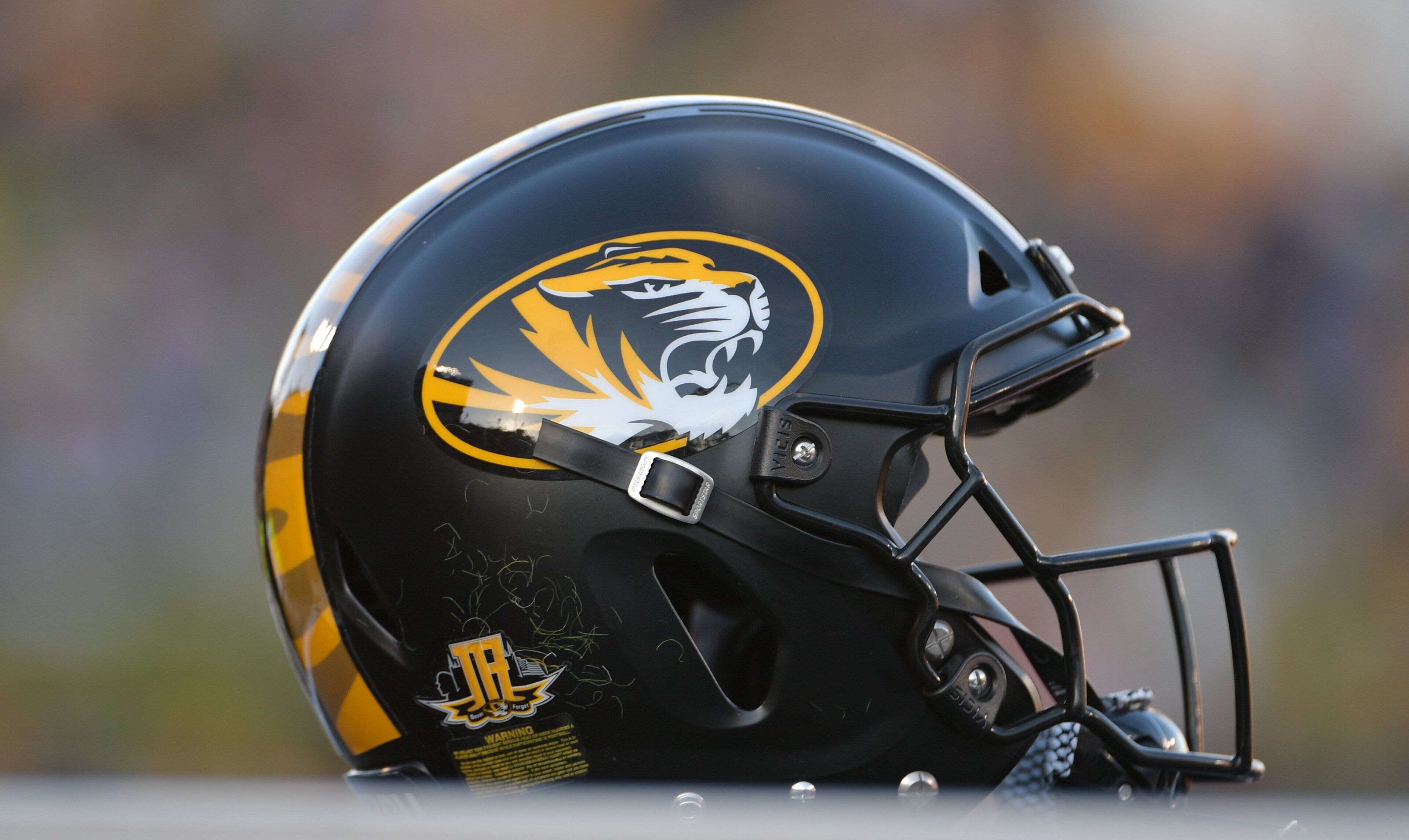 A football helmet with a tiger logo and a warning label.