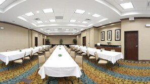Une salle de conférence avec de longues tables, des chaises et un sol recouvert de moquette.