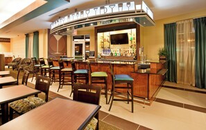 A bar area with a curved counter, multiple seating options including bar stools and tables, and a television mounted above the bar. - Holiday Inn Columbia East by IHG (Columbia)