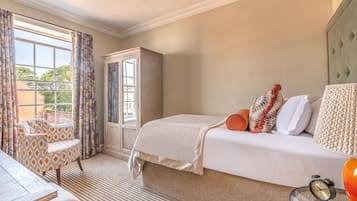 A bedroom with a bed, a chair, a wardrobe, and a window with curtains.
