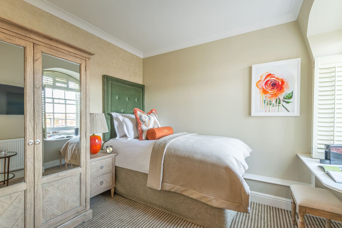 A bedroom with a bed, a dresser, a desk, and a window with blinds.