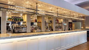 A bar area with a long counter, shelves with bottles, and a ceiling with hanging glasses. - Harbour Hotel Chichester (Chichester)