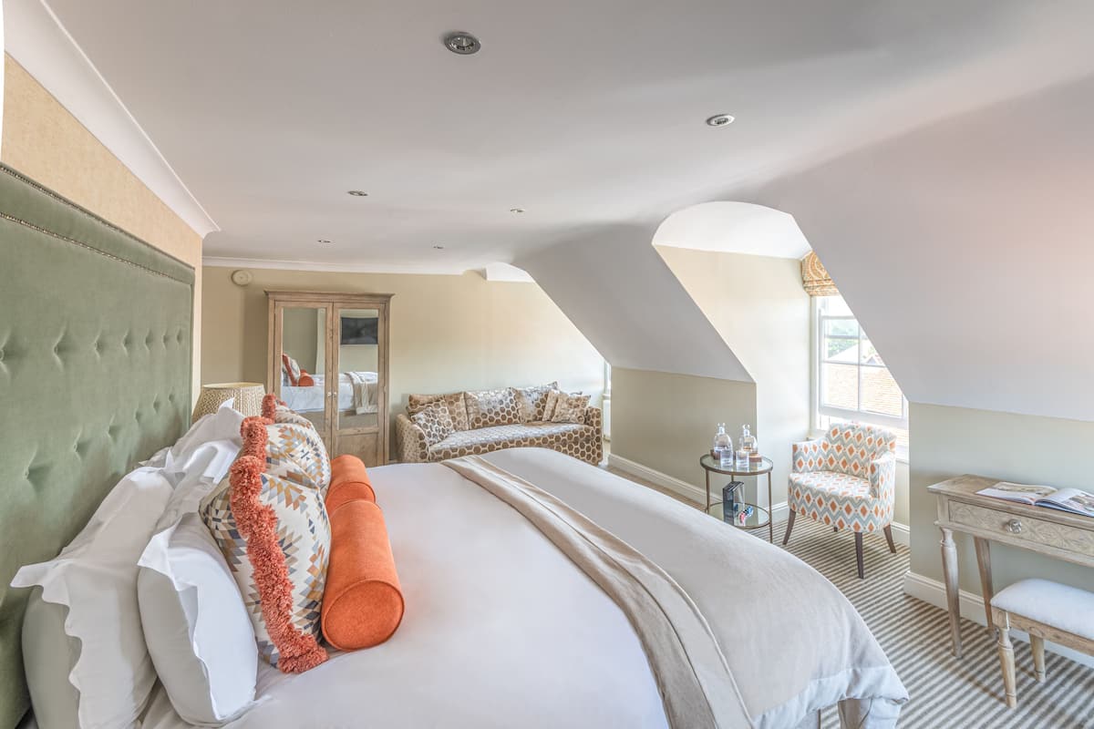 A hotel room with a large bed, a desk, a chair, and a sofa.