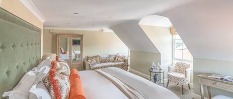 A hotel room with a large bed, a desk, a chair, and a sofa.