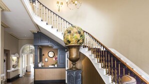 A grand staircase with a decorative globe, a reception desk, and a chandelier. - Harbour Hotel Chichester (Chichester)