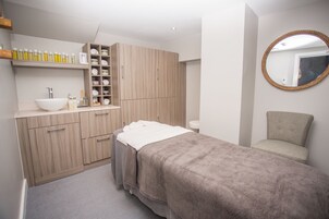 Un moderno cuarto de spa con un mueble grande de madera, un lavamanos blanco y una camilla de masaje.
