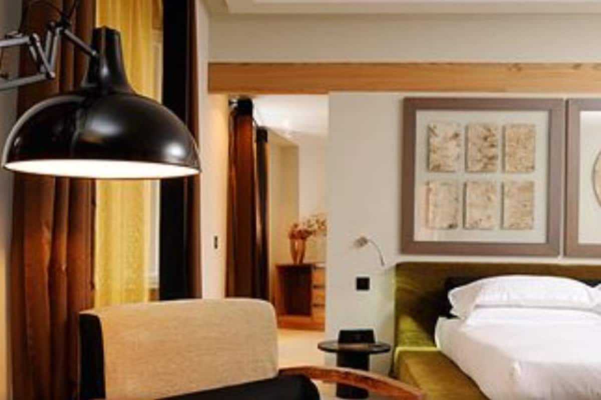 Una habitación de hotel con una cama, una silla, un escritorio y una lámpara.