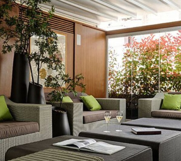 A modern outdoor seating area with wicker furniture, green cushions, and potted plants. - Babuino 181 – Small Luxury Hotels of the World (Rome)