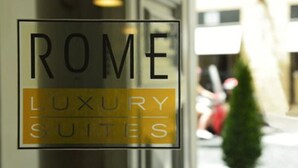 Une enseigne indiquant « ROME LUXURY SUITES », avec une vitre transparente.