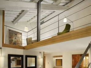 A modern interior with exposed ceilings, a wooden mezzanine, and a staircase. - Babuino 181 – Small Luxury Hotels of the World (Rome)