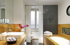 A modern bathroom with a wooden vanity, a large mirror, a bathtub, and a shower area. - Babuino 181 – Small Luxury Hotels of the World (Rome)