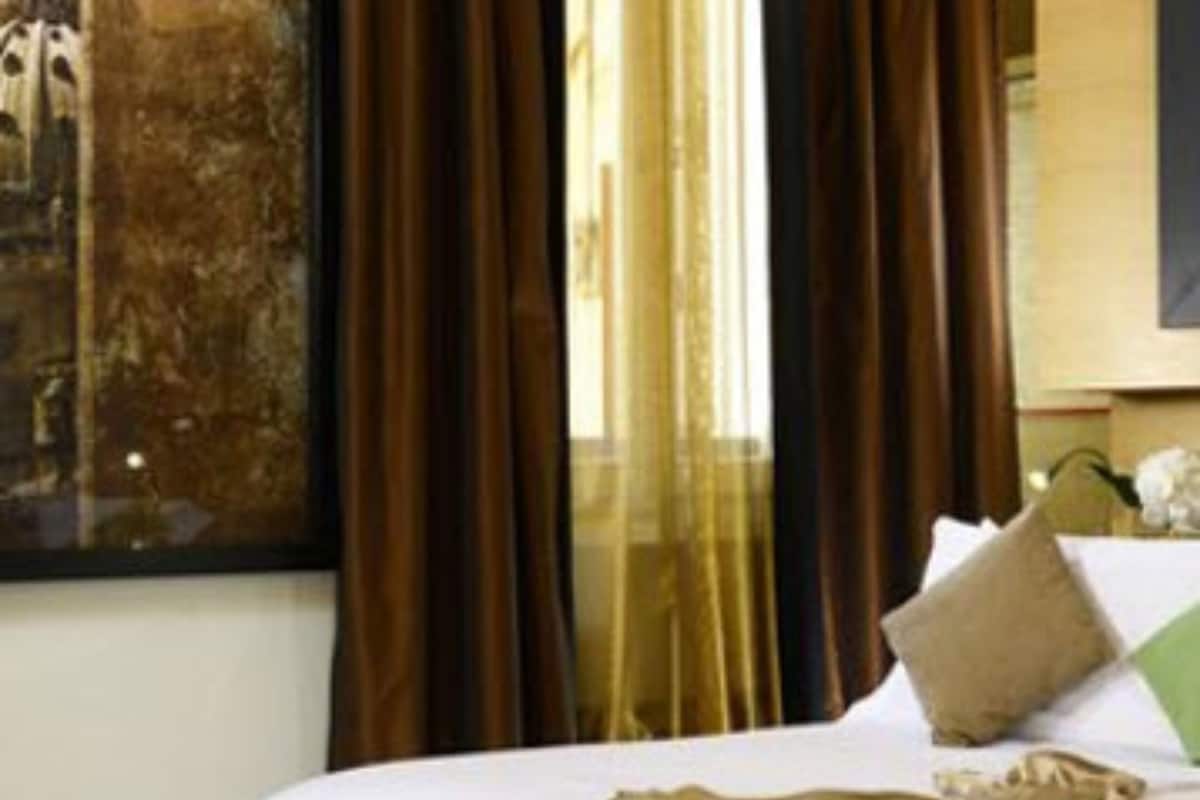 Una habitación de hotel con una cama, un cuadro grande en la pared y cortinas.