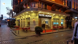 A hotel with a curved facade, outdoor seating, and multiple flags. - Hotel Akcinar (Istanbul)