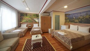 Une chambre d’hôtel avec deux lits, un canapé, une petite table et une vue sur la mer par une grande fenêtre.