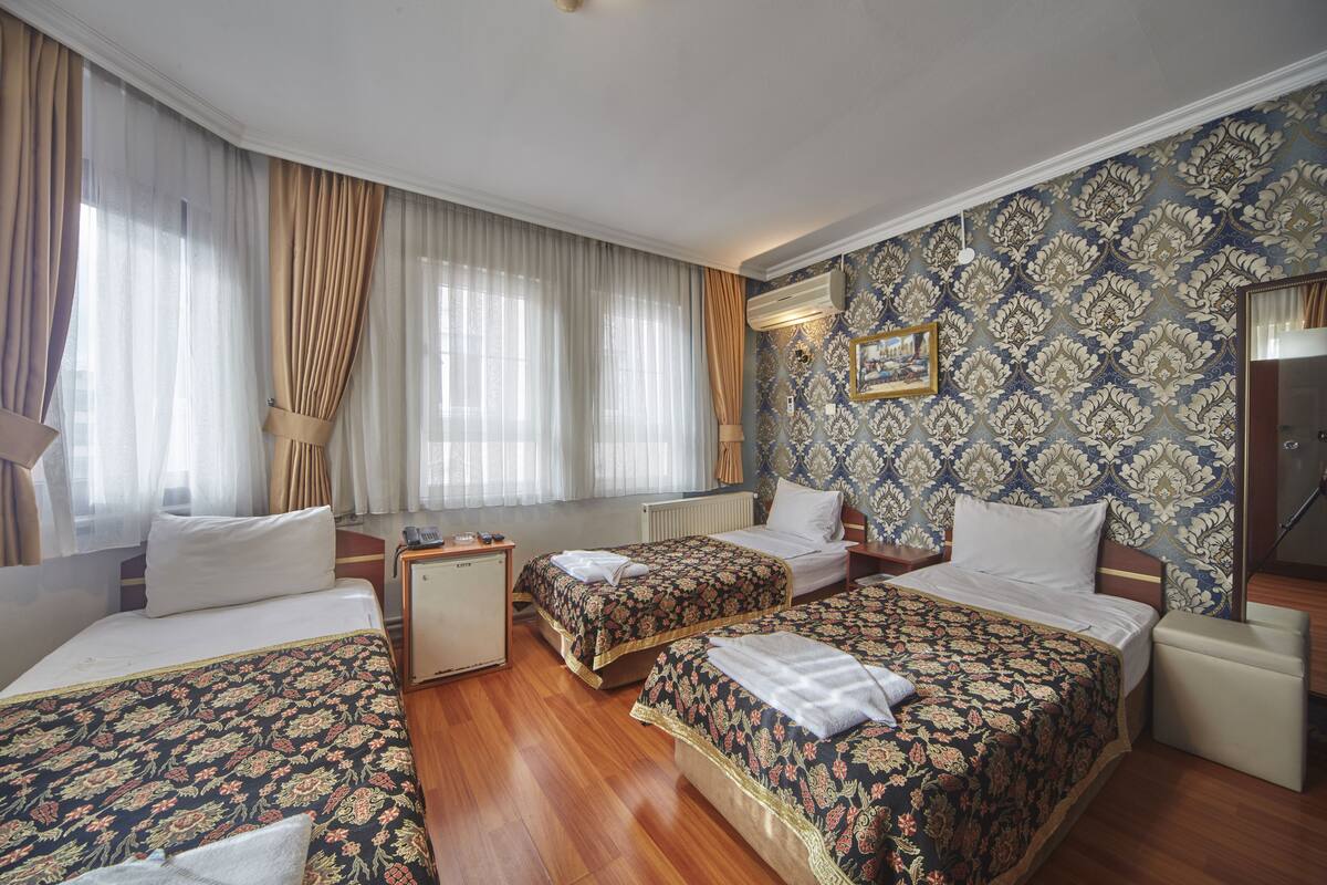 A hotel room with two beds, a small desk, and a radiator.