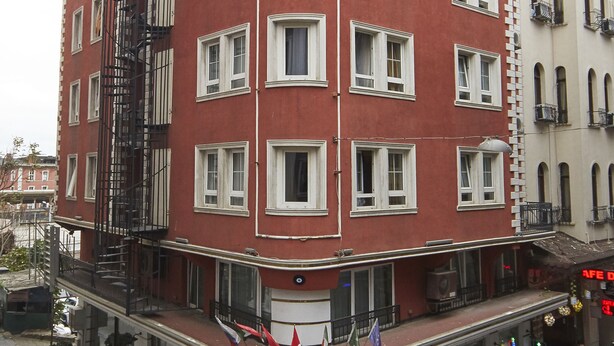 Un immeuble à plusieurs étages, doté d’une façade rouge, de nombreuses fenêtres et d’une échelle de secours.