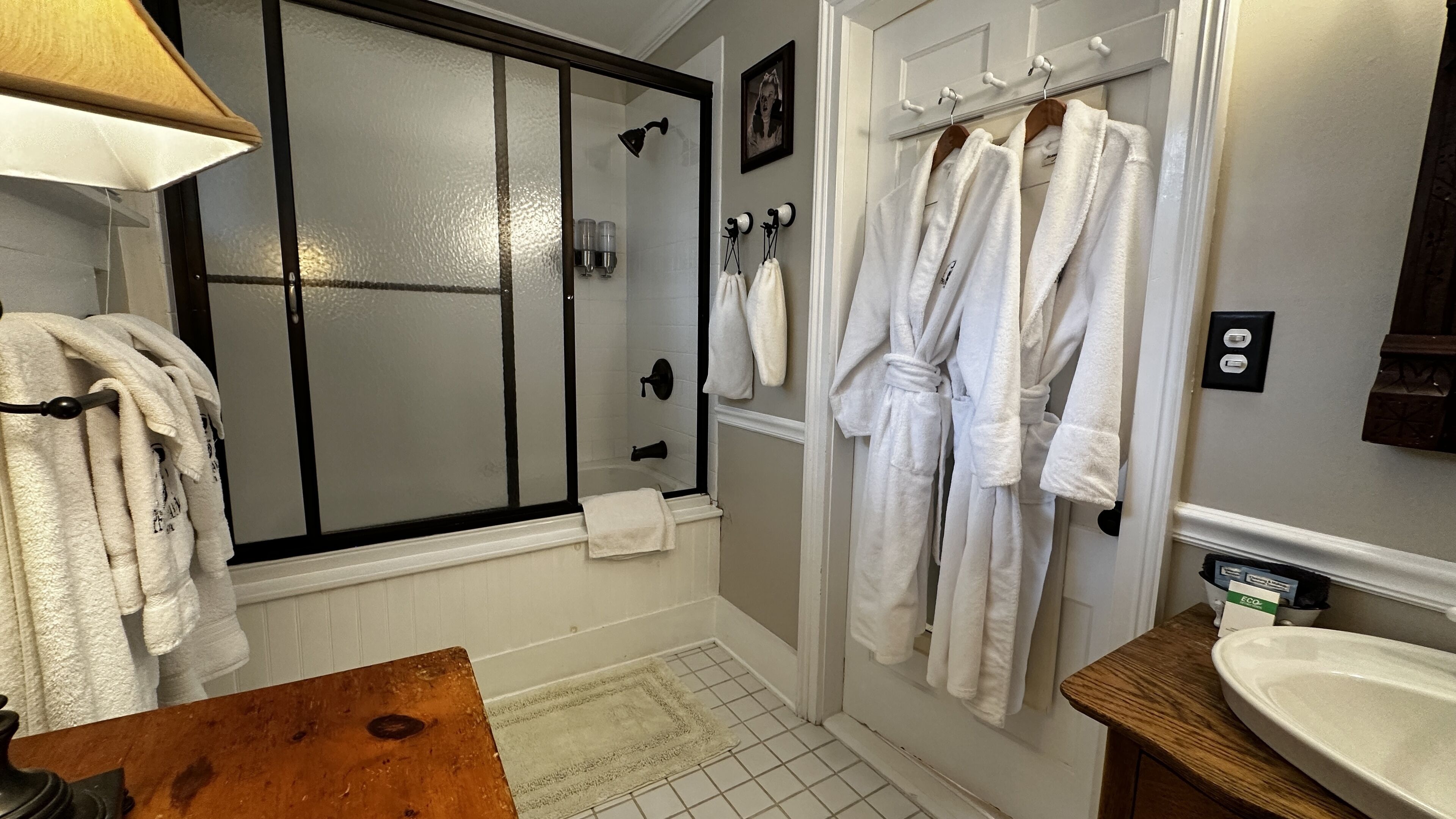 Une salle de bain avec une douche à parois de verre, des serviettes blanches et un meuble-lavabo en bois avec un évier.