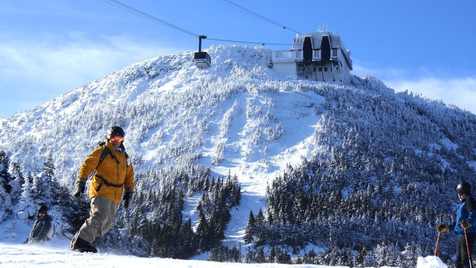 A ski lift on a snowy mountain with a building in the background.