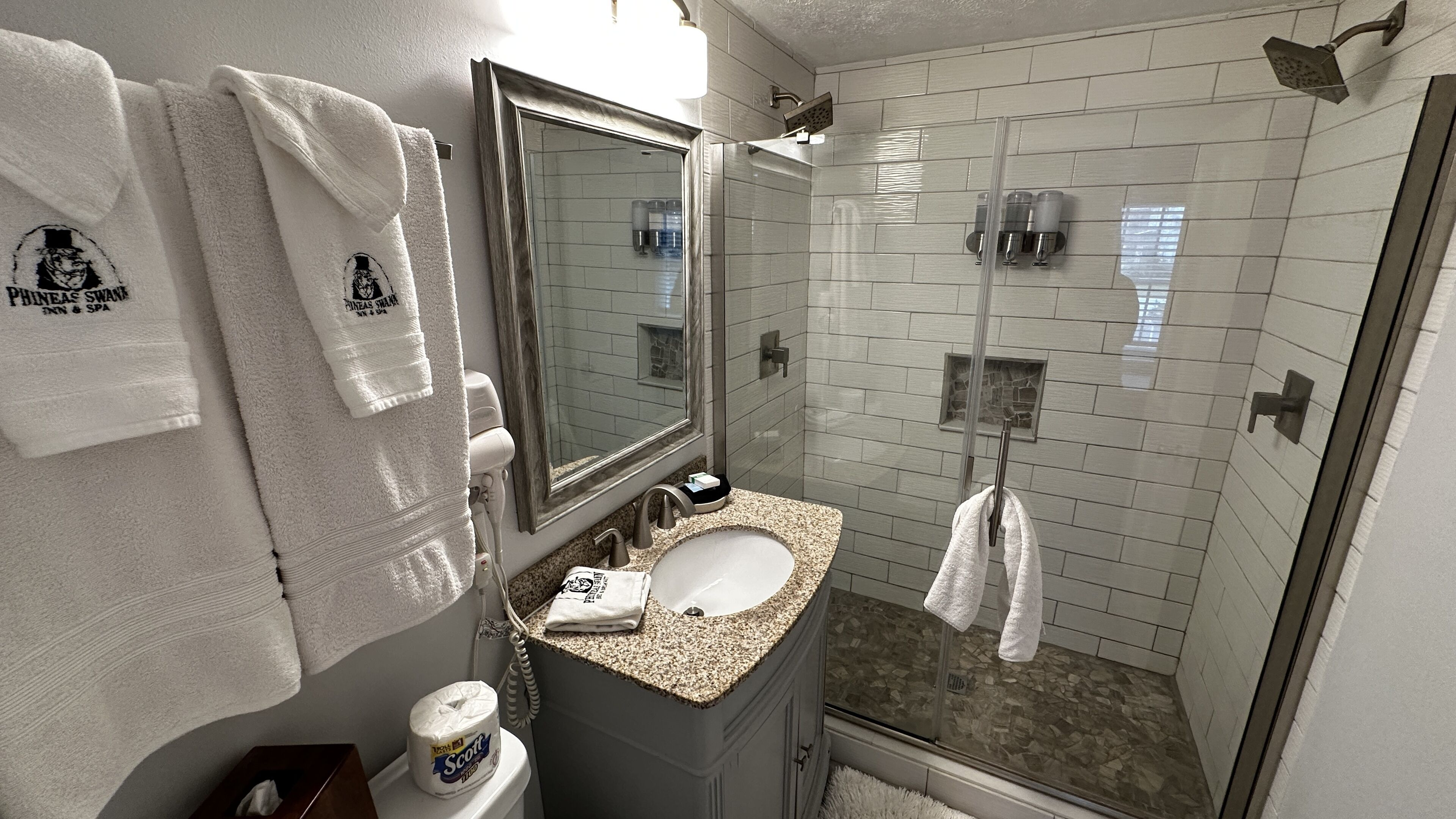 A bathroom with a sink, mirror, towel rack, and shower area.