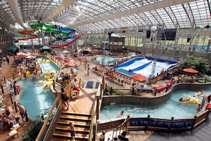Un parque acuático interior con múltiples piscinas, toboganes y una amplia zona cubierta.