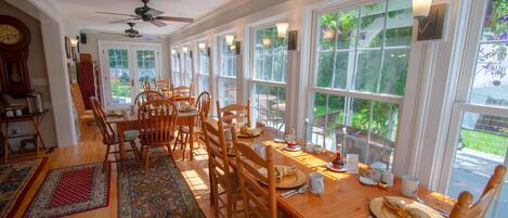 A dining area with a long wooden table, multiple chairs, and a ceiling fan.