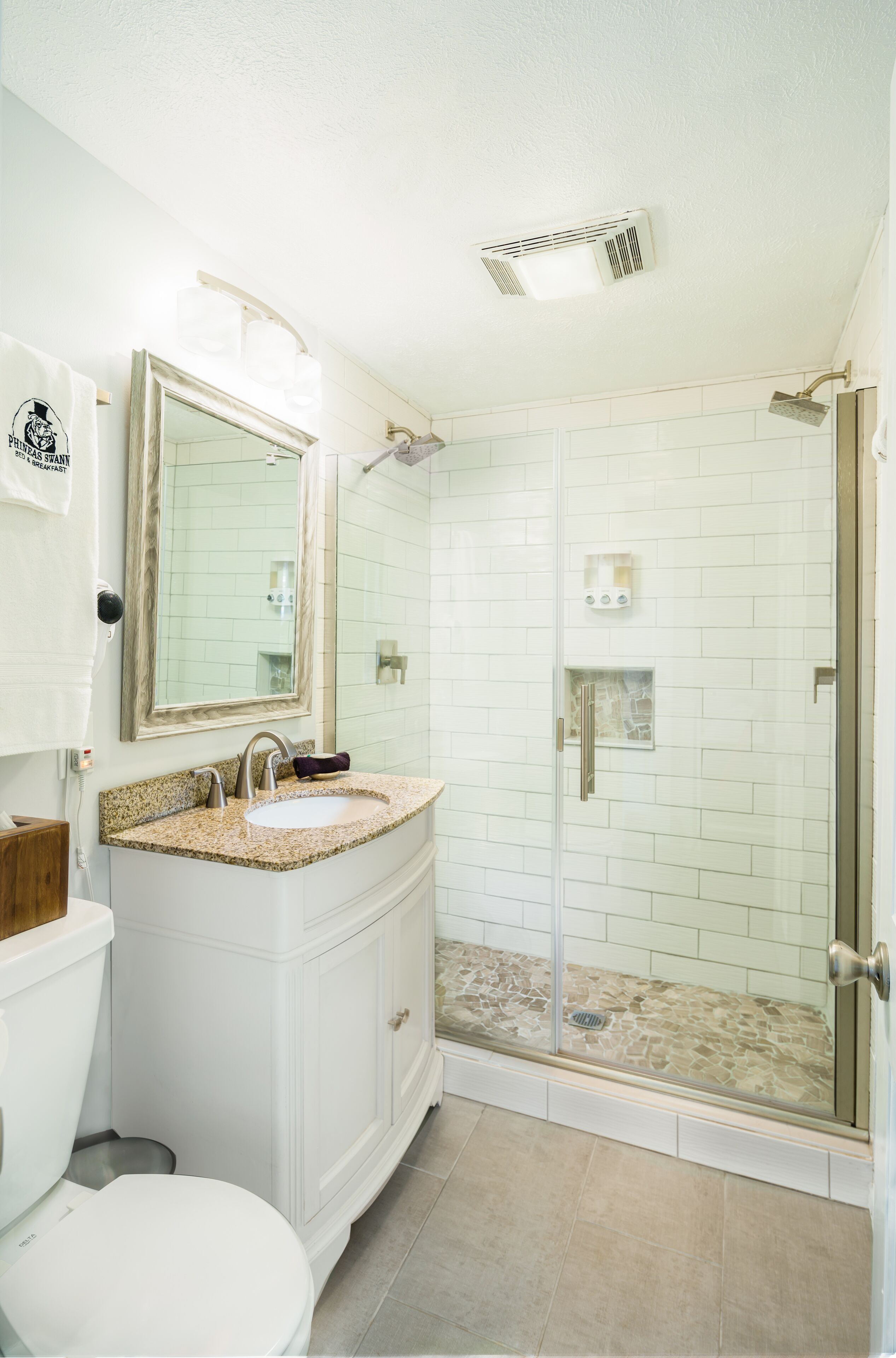 A bathroom with a white vanity, a sink, a mirror, and a glass-enclosed shower area.
