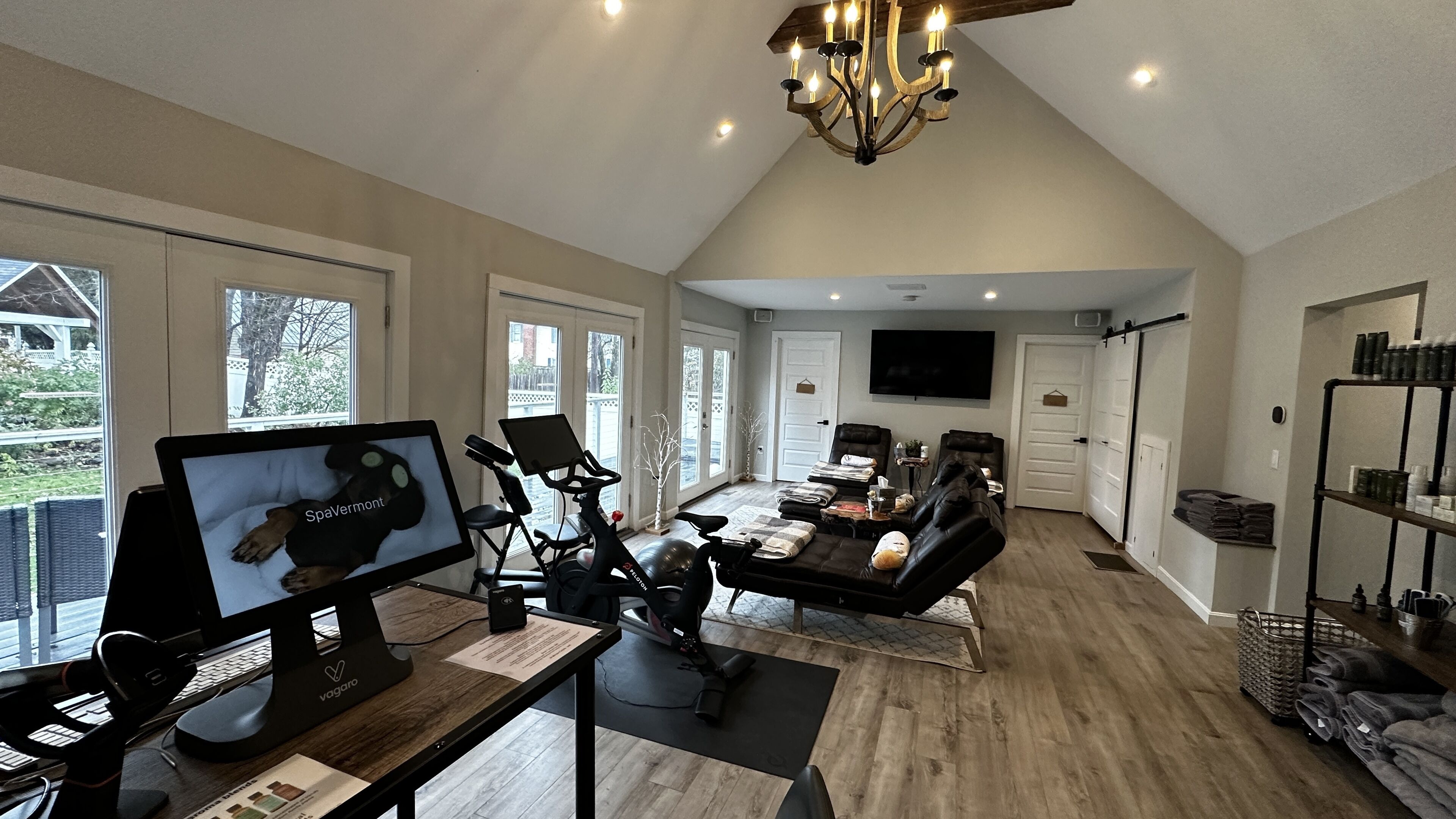 A spacious living area with a treadmill, stationary bike, and exercise balls, a large TV, and a cozy seating area with a fireplace.