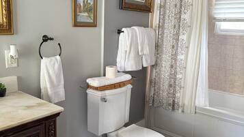 A bathroom with a toilet, a sink, a mirror, framed pictures on the wall, and a shower curtain.