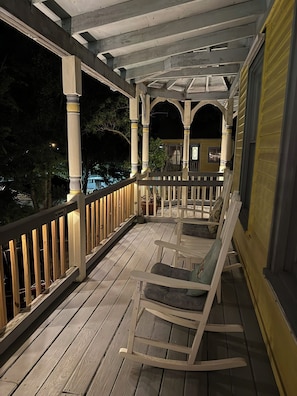 A wooden porch with a railing, a bench, and a covered area with columns.