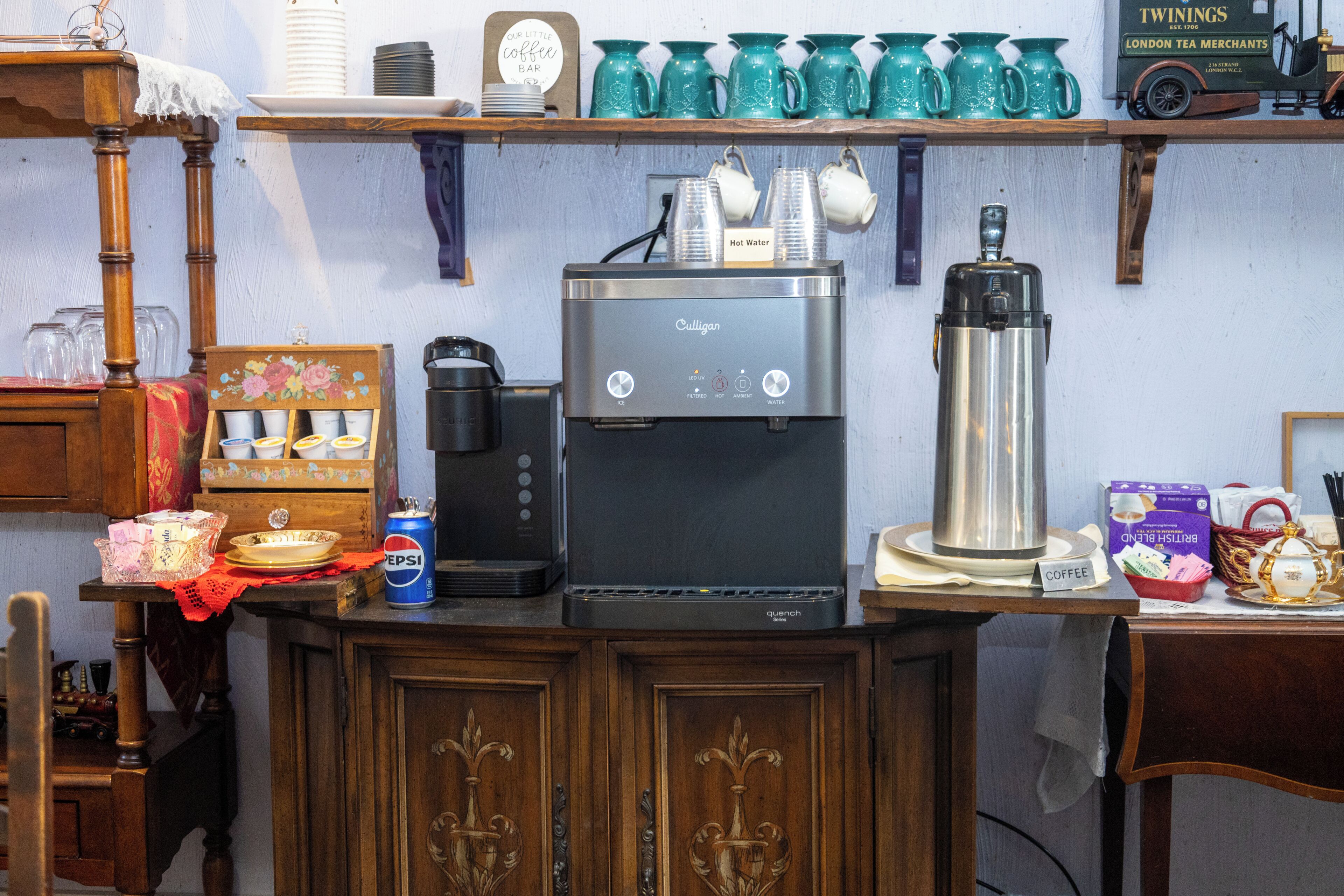 A kitchenette with a coffee maker, a kettle, and a tea kettle on the counter.