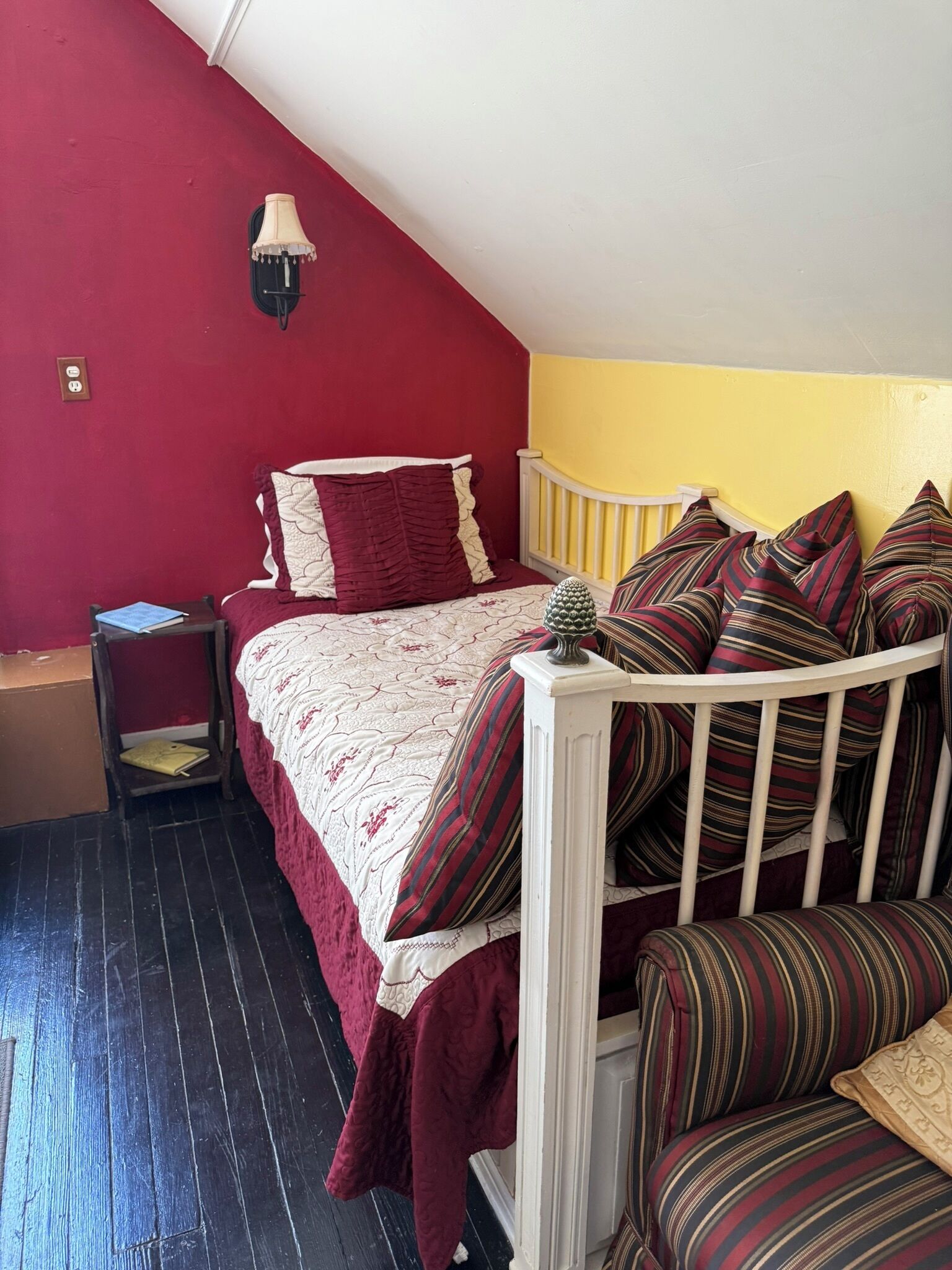 A bedroom with a bed, a nightstand, a lamp, and a chair.