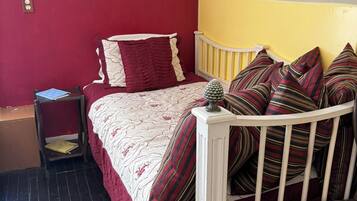 A bedroom with a bed, a nightstand, a lamp, and a chair.