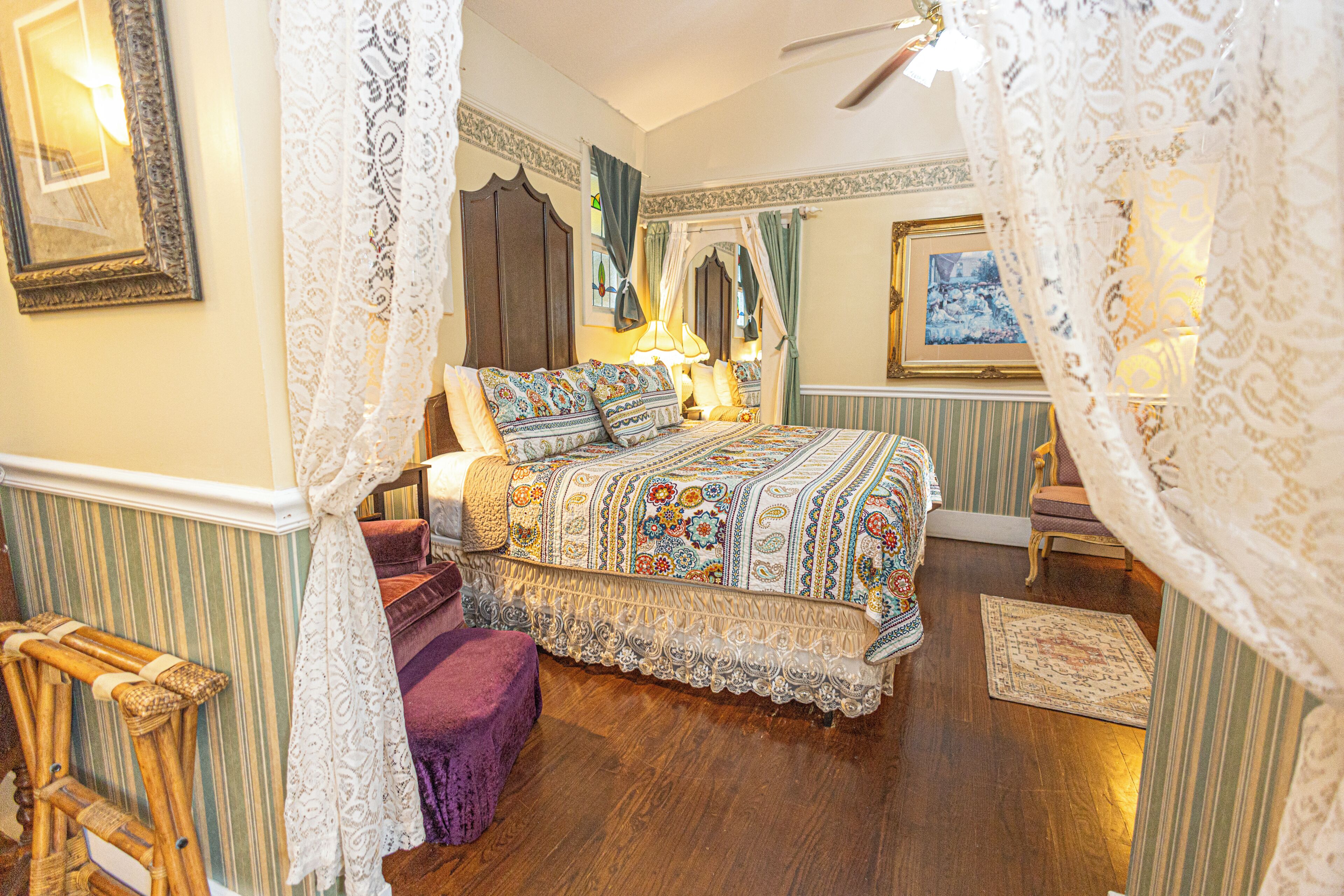 A room with a bed, a chair, a wooden floor, and a window with curtains.